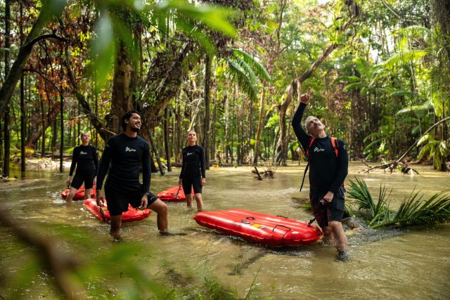 Group of people in a river with rubber rafts in a rainforest.